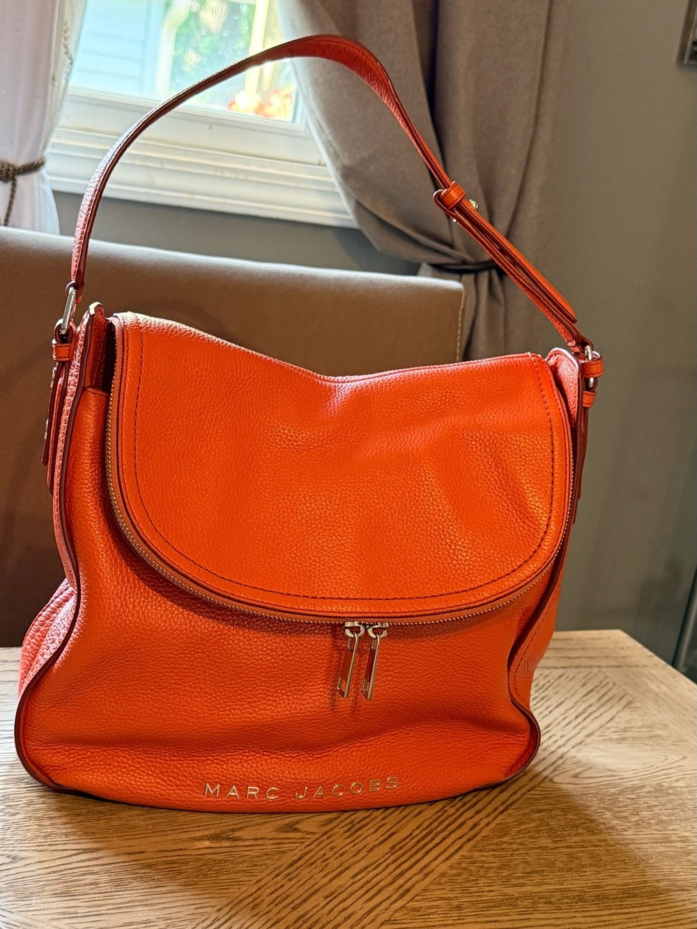 Marc Jacobs The Groove Leather Hobo in a bright orange color.